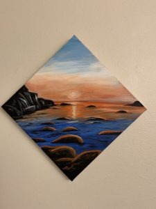 Painting of a sunrise over water with rocks in the foreground. Calm water.